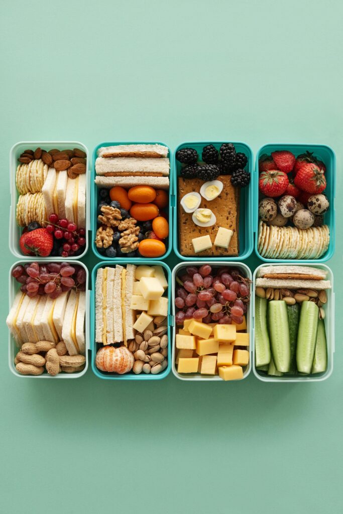 A top view of assorted snacks in teal containers on a green background.